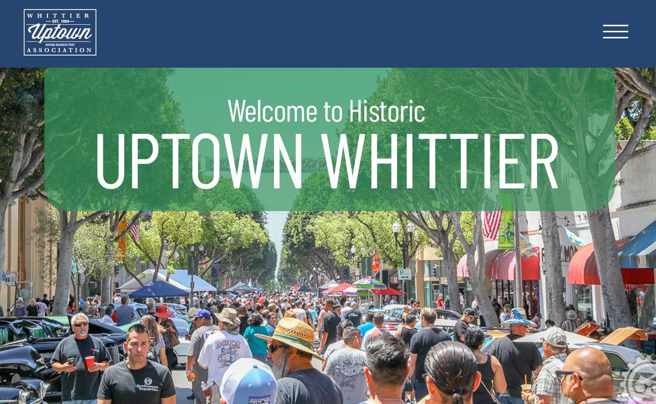 The 2023 Whittier Uptown Association homepage: a navy header with the Association seal, over a photograph of a busy tree-lined street fair, with a green panel reading Welcome to Historic Uptown Whittier.