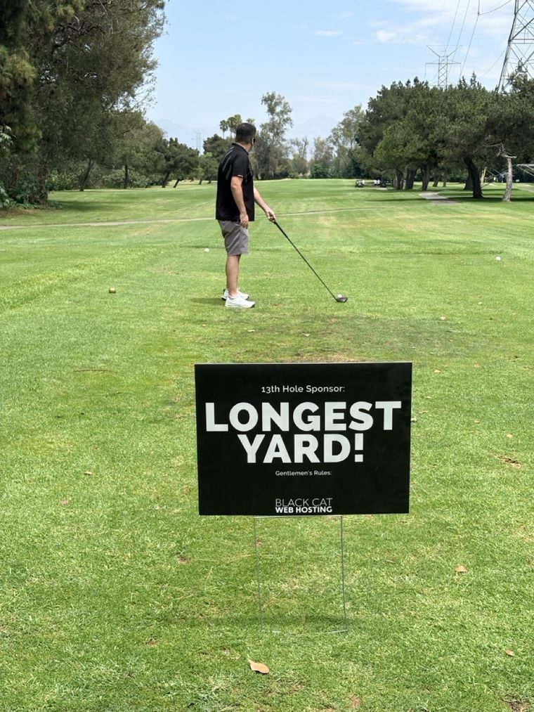 A golfer teeing off past the Longest Yard sign.
